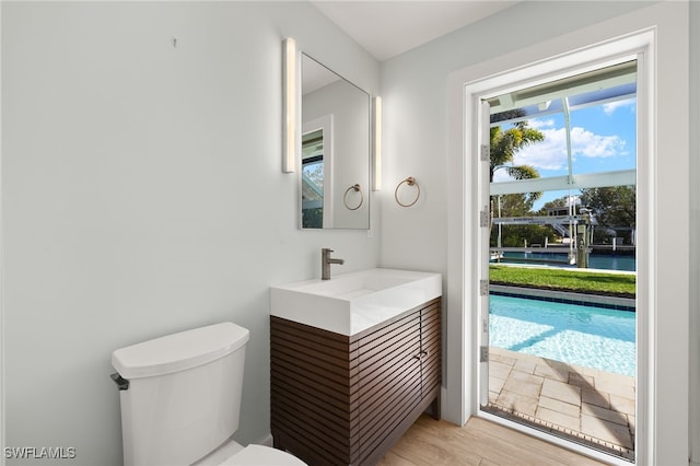 half bath featuring vanity, wood finished floors, and toilet