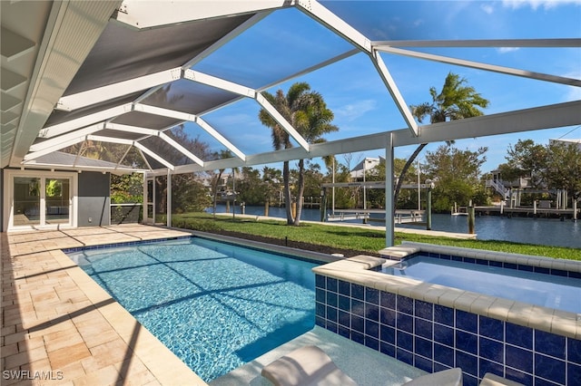 view of swimming pool with glass enclosure, a patio area, a water view, and a pool with connected hot tub