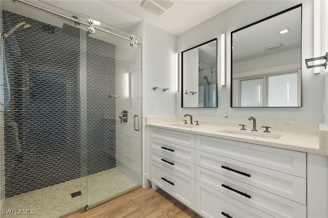 full bath with wood finished floors, a sink, visible vents, and a shower stall