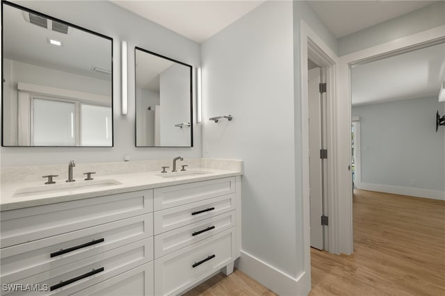 bathroom featuring double vanity, baseboards, a sink, and wood finished floors