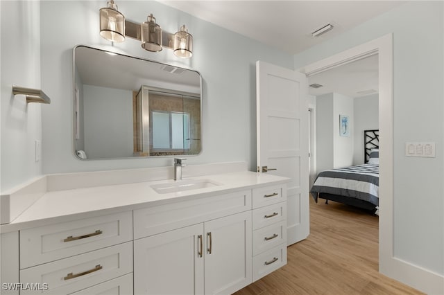 ensuite bathroom with visible vents, vanity, ensuite bath, and wood finished floors