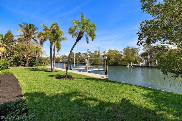 view of dock with a water view, boat lift, and a yard