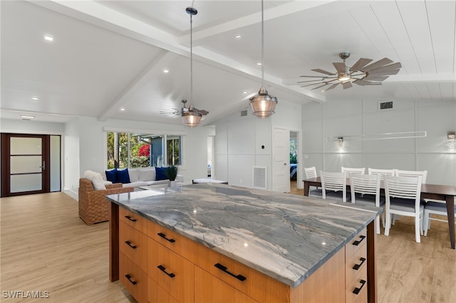 kitchen with light wood-type flooring, lofted ceiling with beams, open floor plan, and dark stone countertops