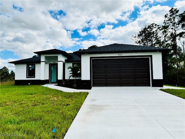 prairie-style house with a garage, a front lawn, concrete driveway, and stucco siding