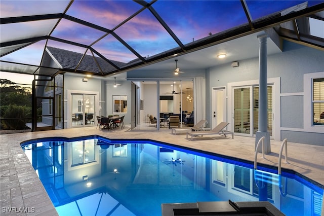 pool at dusk with a patio, a ceiling fan, outdoor dining space, a lanai, and an outdoor pool