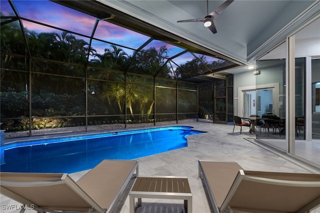 pool at dusk featuring ceiling fan, a patio, glass enclosure, and an outdoor pool