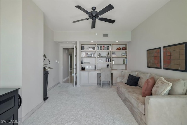 living room with visible vents, baseboards, ceiling fan, light colored carpet, and built in study area