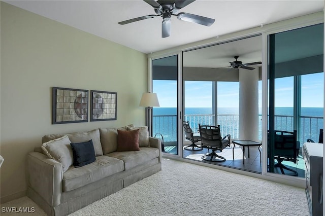 carpeted living room with expansive windows, a water view, and ceiling fan