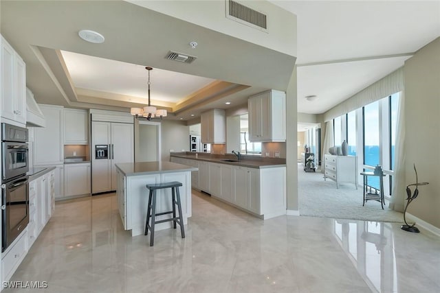 kitchen featuring a tray ceiling, visible vents, paneled built in refrigerator, and a notable chandelier