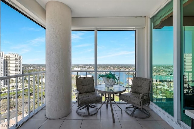 sunroom featuring a city view, a water view, and a healthy amount of sunlight