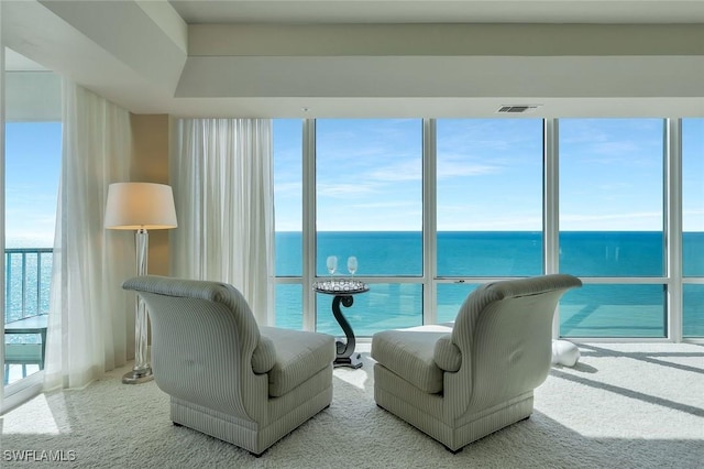 carpeted living room featuring visible vents and a water view