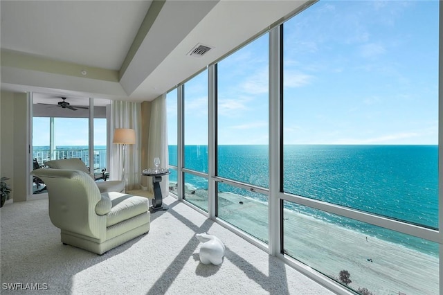 living area featuring a ceiling fan, visible vents, a water view, and expansive windows