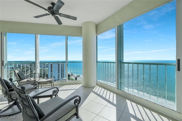 sunroom with a ceiling fan and a water view