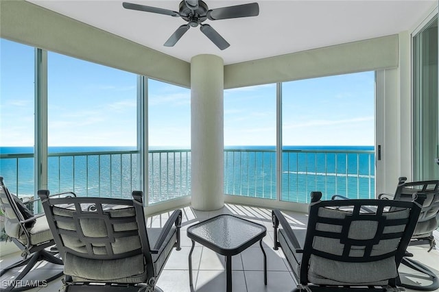 sunroom featuring a water view and ceiling fan