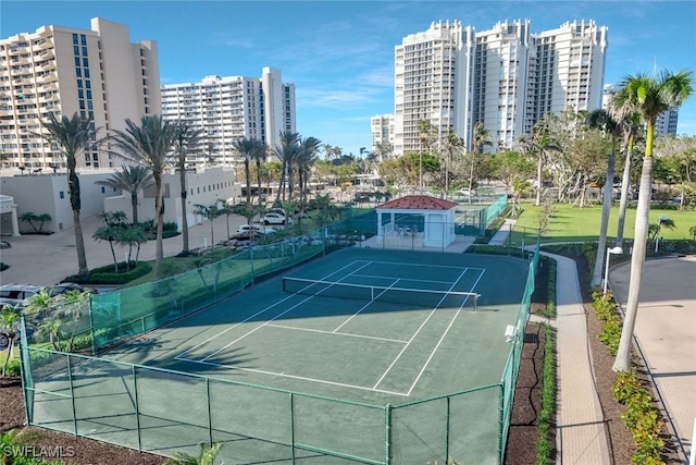 view of tennis court with a city view and fence