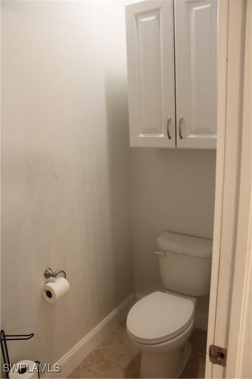 bathroom with tile patterned flooring, baseboards, and toilet