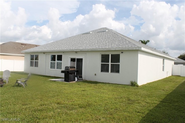 back of house featuring a shingled roof, stucco siding, a yard, and fence