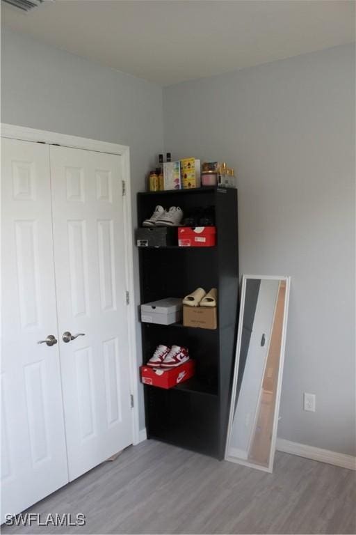 interior space featuring a closet, wood finished floors, visible vents, and baseboards