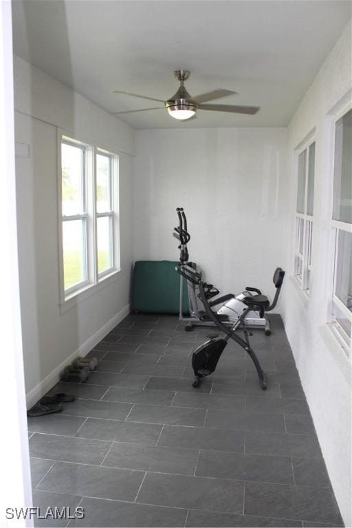 exercise area with ceiling fan and baseboards