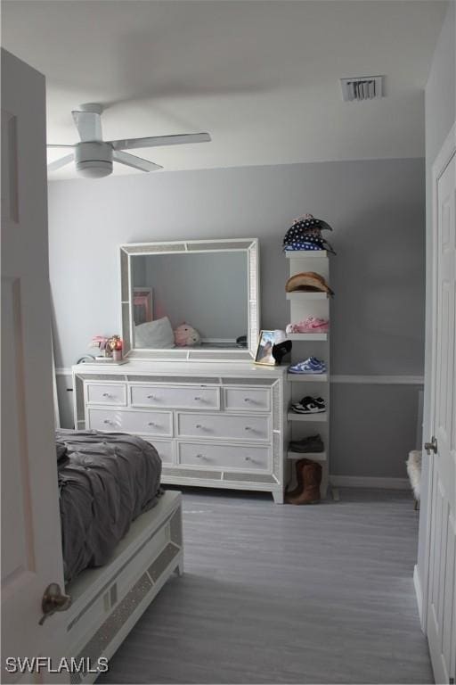 bedroom with baseboards, dark wood-type flooring, visible vents, and a ceiling fan