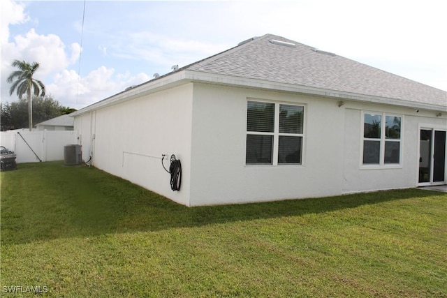 view of property exterior with central AC, a yard, and roof with shingles