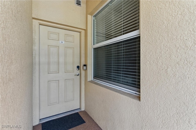 entrance to property with stucco siding and visible vents