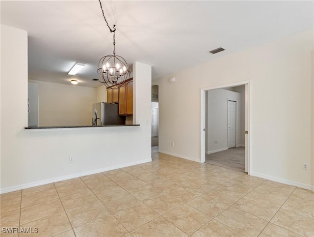 unfurnished room with baseboards, visible vents, and a chandelier