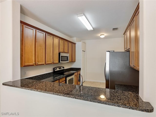 kitchen featuring a peninsula, visible vents, stainless steel appliances, and dark stone counters