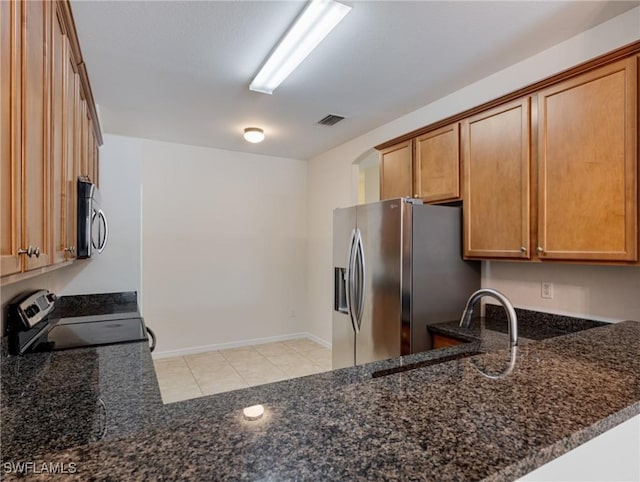 kitchen with stainless steel appliances, visible vents, a sink, dark stone counters, and a peninsula