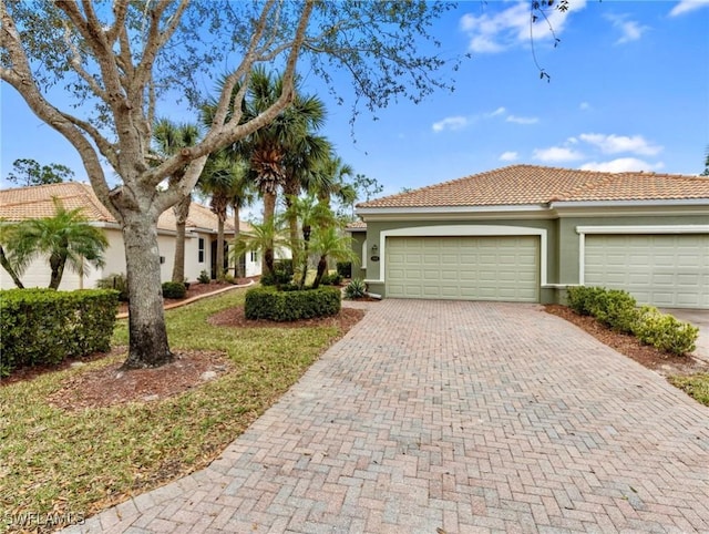 view of front of home featuring a tiled roof, decorative driveway, and stucco siding