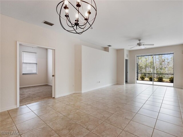 empty room with light tile patterned floors, ceiling fan with notable chandelier, visible vents, and baseboards