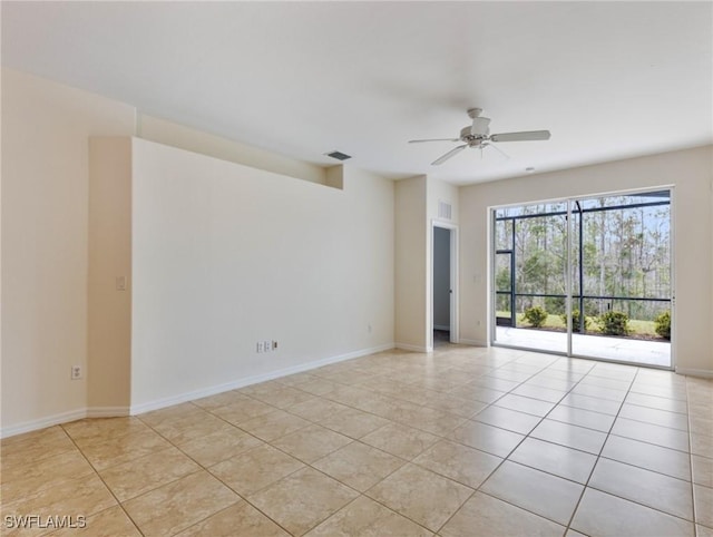 spare room with light tile patterned flooring, a ceiling fan, and baseboards