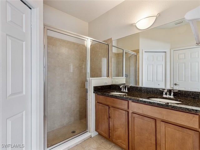 bathroom with double vanity, a stall shower, a sink, and tile patterned floors