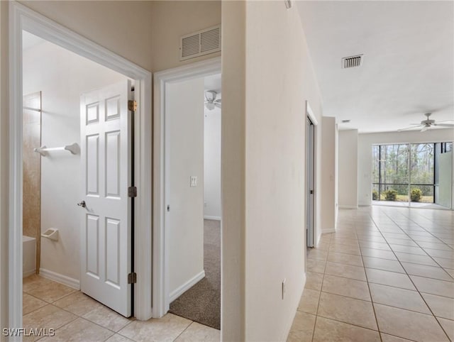 hall with visible vents, baseboards, and light tile patterned floors