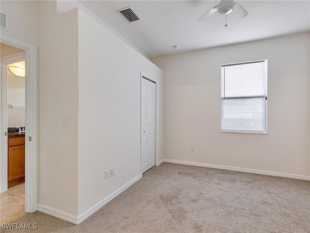 unfurnished bedroom featuring light carpet, baseboards, visible vents, ceiling fan, and a closet