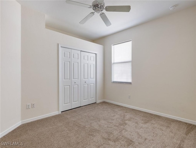 unfurnished bedroom featuring a ceiling fan, a closet, baseboards, and carpet flooring