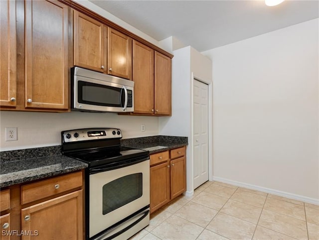 kitchen with electric range, stainless steel microwave, and brown cabinetry