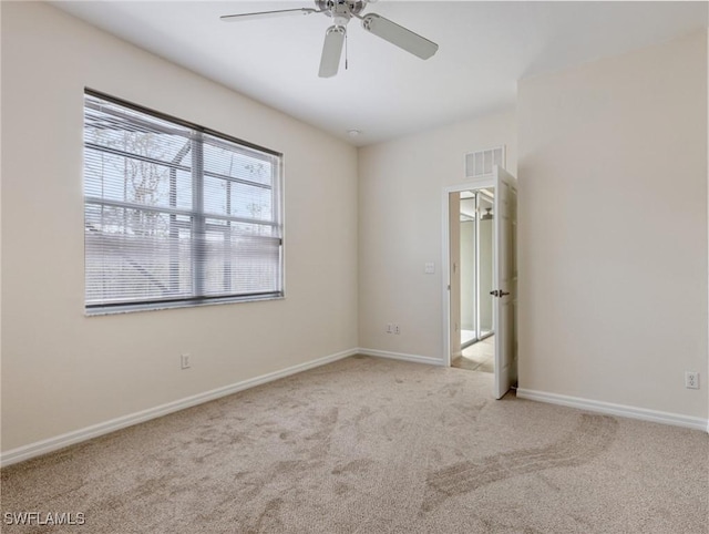 empty room with a ceiling fan, carpet flooring, visible vents, and baseboards