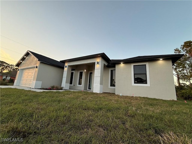 view of front of house featuring a garage, a lawn, and stucco siding