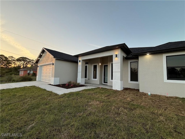 exterior space featuring a yard, driveway, an attached garage, and stucco siding