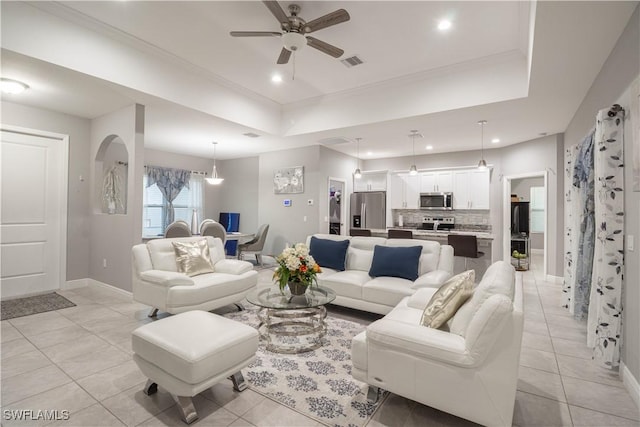 living room featuring arched walkways, a raised ceiling, visible vents, and recessed lighting