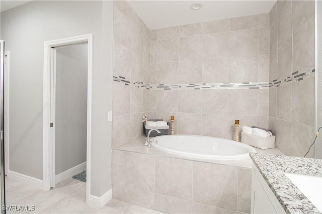 bathroom with tile patterned flooring, baseboards, a bath, and vanity