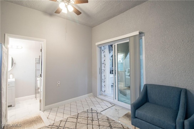 sitting room featuring marble finish floor, ceiling fan, baseboards, and a textured ceiling