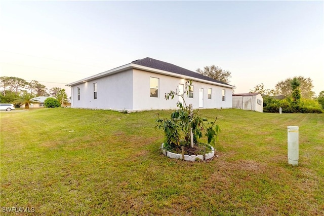 rear view of house featuring a lawn and stucco siding