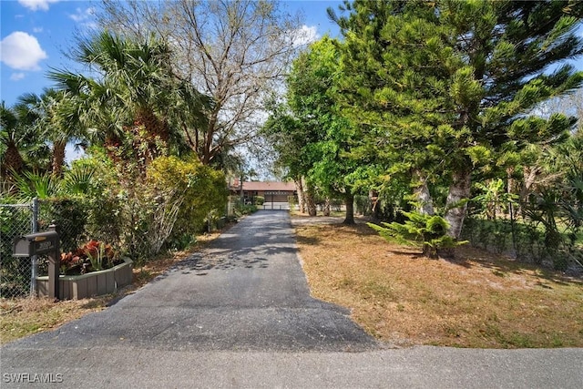 view of property hidden behind natural elements with a garage and fence