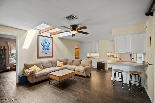 living area featuring dark wood-style floors, ceiling fan, a skylight, and visible vents