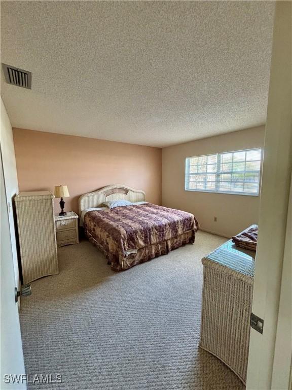 carpeted bedroom with a textured ceiling and visible vents