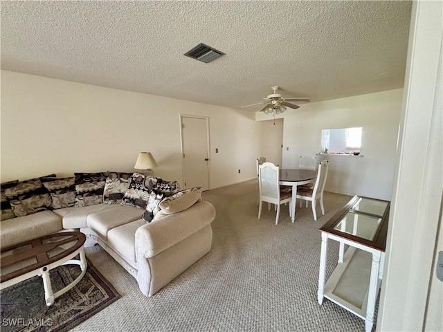 carpeted living area featuring ceiling fan, visible vents, and a textured ceiling