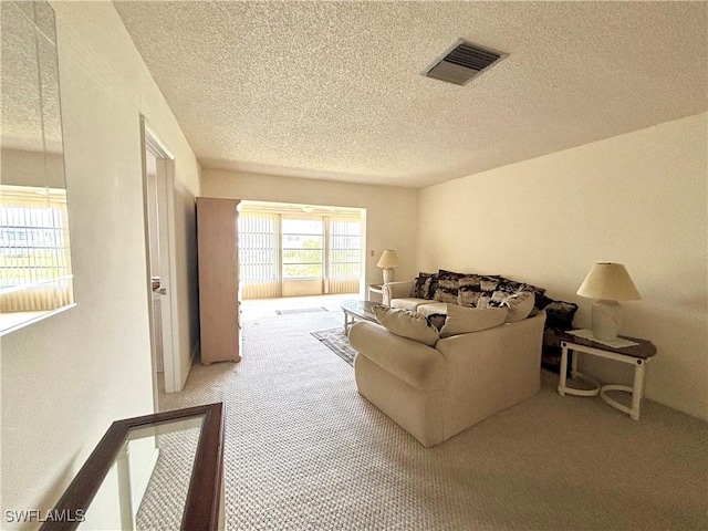 living room featuring a textured ceiling, carpet flooring, and visible vents