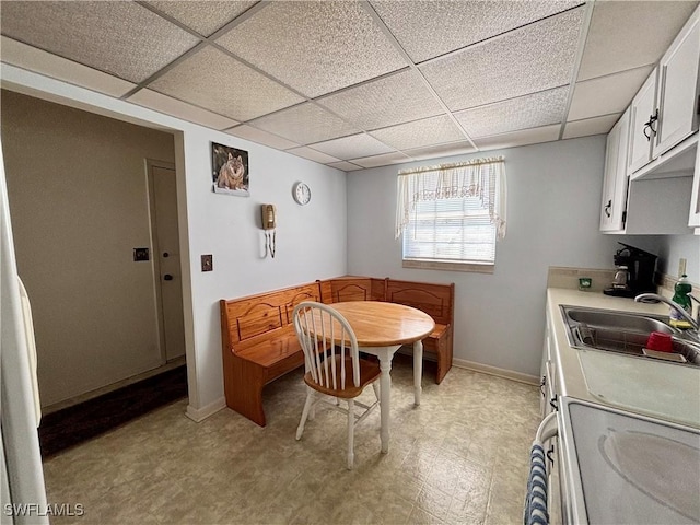 dining room with a paneled ceiling, baseboards, and light floors